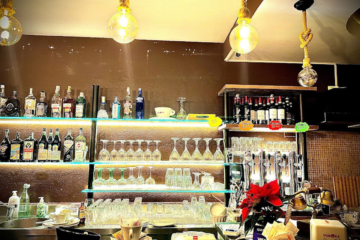 Bancone di Lo Storico con mensole in vetro illuminate, bottiglie di liquori, calici, spillatori e stella di Natale
